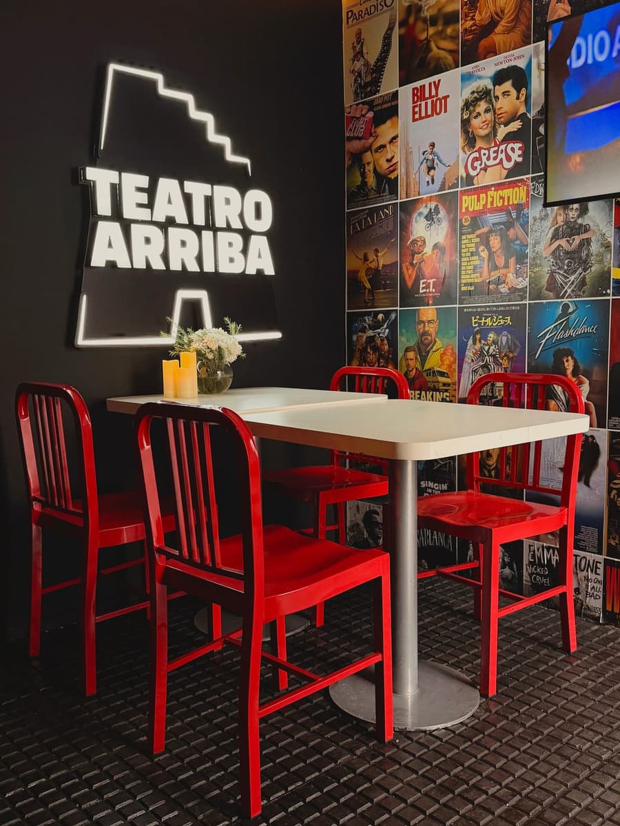 Recepción de Teatro Arriba con cartel de neón y mesa